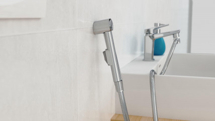 Metallische Handbrause mit flexiblem Brauseschlauch und Verpackung im Hintergrund.